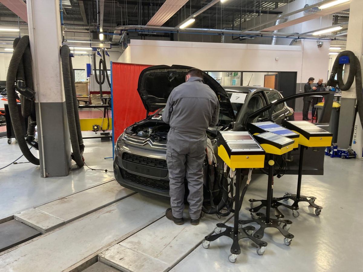 Un mécanicien apprenti travaille sur le faisceau électrique d'une Citroën C3